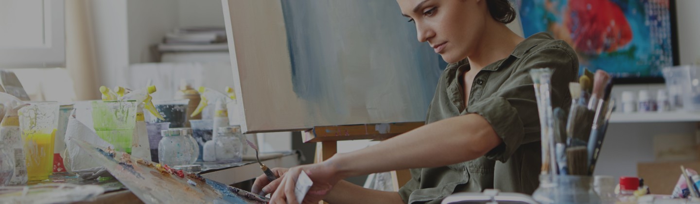 A woman at an easel, painting with oil colours