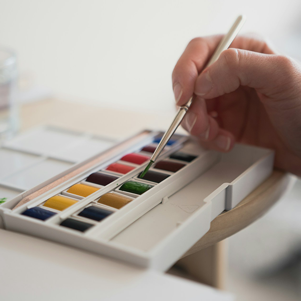 Close up of an artist dipping their brush into som